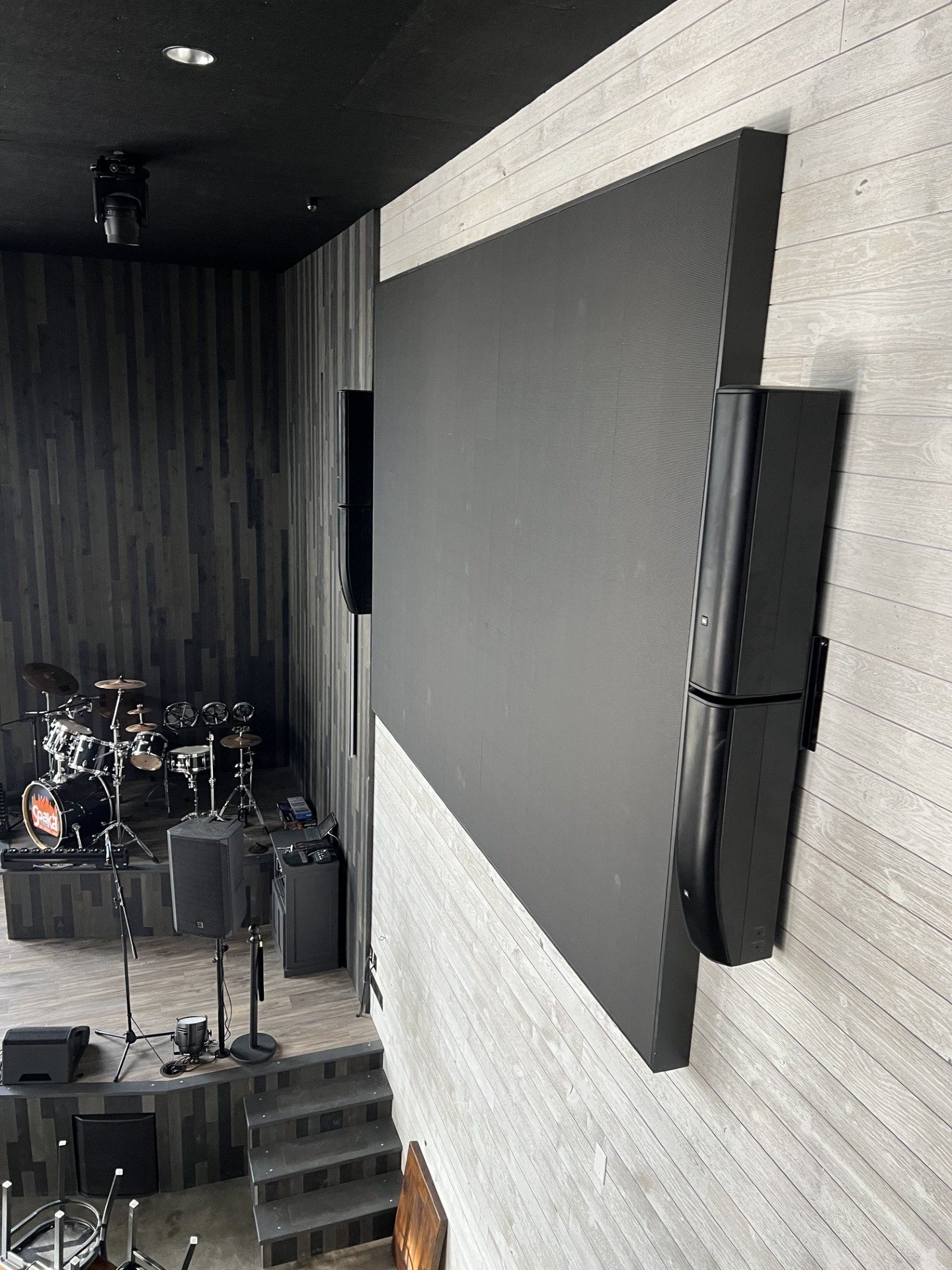 Televisions and speakers mounted above a busy restaurant bar