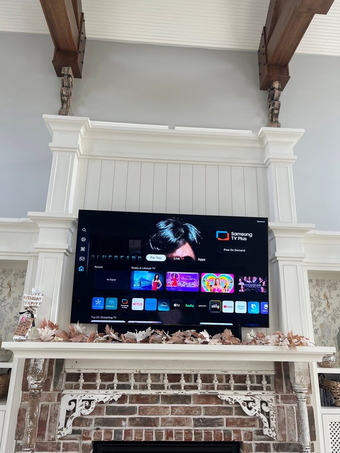 Pull down TV mount on a traditional white mantel