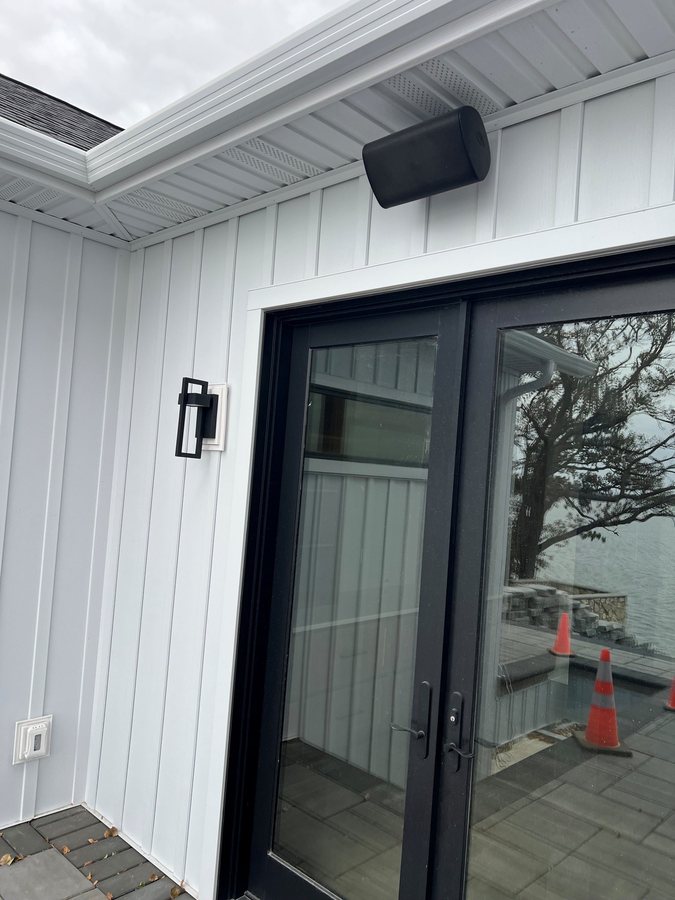 Weatherproof speaker mounted above a patio door