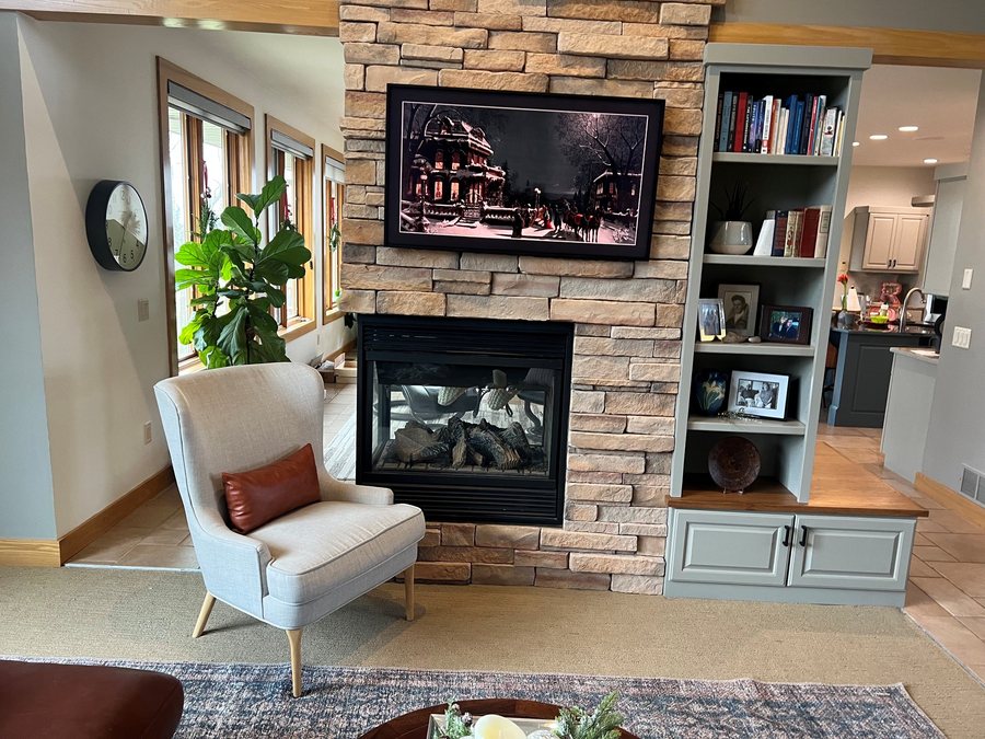 Stone fireplace with a mounted TV and built in shelving