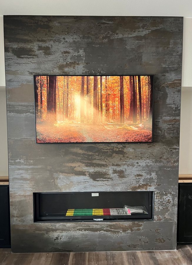 Metal finish feature wall with a flush TV and fireplace